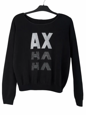 Svart Armani exchange tröja med tryck - Svart långärmad tröja från Armani Exchange med stort silvrigt AX-tryck och dekorerad text HA HA framtill. Rund halsringning och ribbade muddar. Gott skick
