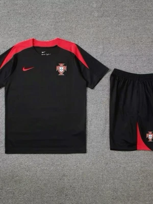 Portugal Nike svart träningsset - Svart träningsset från Nike med Portugals landslagslogga. T-shirten har röda detaljer på axlar och logga på bröstet, och shortsen har matchande röd detalj och logga. Perfekt för fotbollsträning eller sportiga aktiviteter.