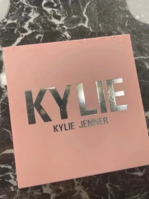 Kylie Jenner blush - Säljer en Kylie Jenner Pressed Blush Powder i färgen 335 Baddie On The Block. Rougen kommer i en snygg ljusrosa fyrkantig dosa med spegel och har en varm persikotonad nyans. Perfekt för att ge kinderna en fräsch och naturlig glow. använd endast 2-3 gånger 