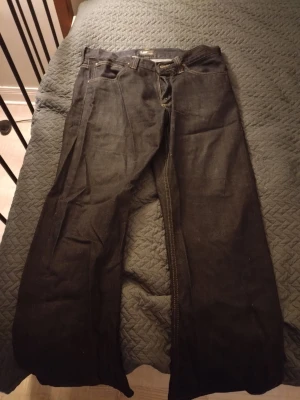 Mörkblå Lee jeans med bootcut - Säljer ett par mörkblå jeans från Lee med bootcut passform. Jeansen har klassiska fem fickor, kontrastsömmar och Lee-logga på bakfickan. Materialet är denim och modellen har en något vidare benform. Perfekt för dig som gillar retrostil.