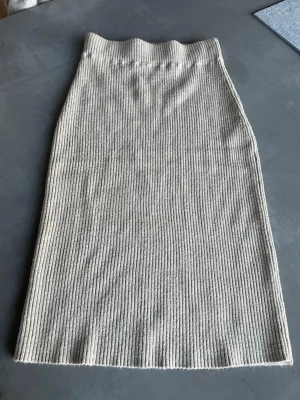 Rbbstickad midikjol - Beige ribbstickad midikjol från Vila.  Perfekt att styla med en enkel topp eller stickad tröja för en avslappnad look.