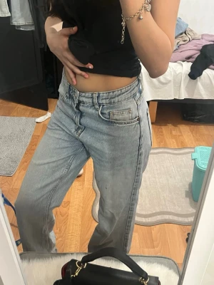 Ljusblåa raka jeans med hög midja - Säljer ett par ljusblå jeans med raka ben och hög midja. Jeansen har klassisk femficksdesign och stängs med dragkedja och knapp. Perfekta för en avslappnad och trendig look. Materialet är denim i bomull.