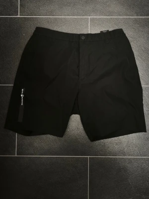 Svarta shorts - SAIL RACING - Snygga svarta shorts från Sail Racing med dragkedjeficka på sidan och klassisk passform. Perfekta för sommarens alla äventyr. Materialet känns slitstarkt och bekvämt, och designen är stilren med diskret logga på benet. PERFEKT för sommaren. Storlek M men känns som S-M.