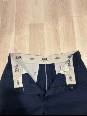 Mörkblå Dickies 874 Original Fit chinos - Säljer ett par mörkblå Dickies 874 Original Fit chinos med klassisk rak passform. Byxorna har hällor för bälte, bakficka med Dickies-logga och dragkedjegylf. Materialet är slitstarkt och passar perfekt till en streetwear-look.
