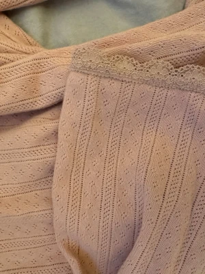 Ljusrosa blus från &other Stories  - Säljer en ljusrosa blus från other Stories med fina spetsdetaljer längs halsringningen. Den är trekvarts ärmard vilket gör den perfekt till våren/sommaren. Blusen är gjort i mjuk bomull och har ett diskret prickigt mönster med små hålmönster och ribbade ränder. Perfekt för middagar eller vardag.