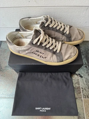 Grå Saint Laurent  - Snygga dojjor inför sommarn. Använda men fortfarande i användbart skick, sulorna har bra grepp kvar.‼️NYPRIS:ca7000kr‼️Storleksmässigt skulle jag säga dem e större! Så passar säkert ngn me 43-44.  ⚠️ Obs: Kanterna e limmade, inget som påverkar användningen.  Kommer me box & dustbag.💯