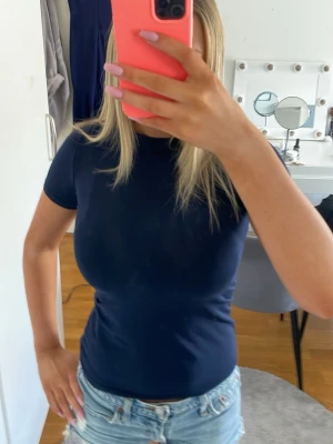 Mörkblå tight t-shirt i bomull - Säljer en mörkblå, tight t-shirt i mjuk bomull. T-shirten har korta ärmar och rund halsringning, perfekt för en enkel och stilren look. Passformen är figurnära och materialet känns skönt mot huden.
