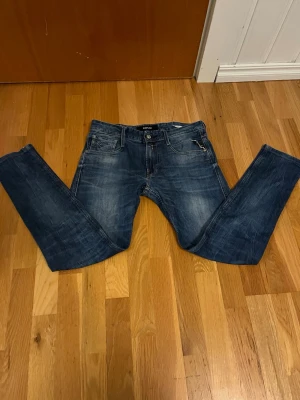 Blå jeans från Replay - Snygga blå jeans från Replay med klassisk femficksdesign och diskreta slitningar framtill. Jeansen har raka ben och normal midja. Tillverkade i denim med en cool tvättad look och detaljerade bakfickor.