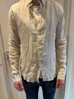 John Henric linneskjorta - Biege linneskjorta från John Henric 100% linne. Passform slim fit. Skjortan är aldrig använd och tagen är kvar. 