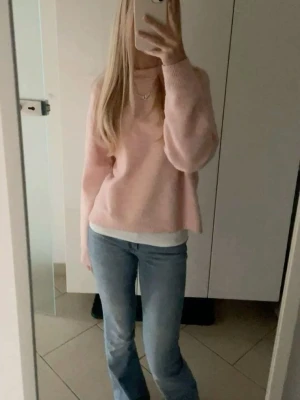 Ljusrosa stickad tröja - Mysig ljusrosa stickad tröja med avslappnad passform och rund halsringning. Perfekt att matcha med jeans eller kjol för en chill och stilren look.