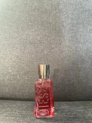 Diesel parfym med vågig flaska - Cool parfym från Diesel i en vågformad glasflaska med rosa/röd ton och silverfärgad kork. Använd max 10 gånger