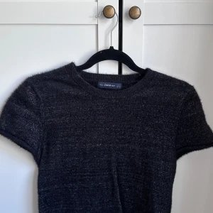 Svart glittrig stickad sett från zara 🩷 - Stickat sett med en kortärmad topp och en långkjol, det är svart tyg med flerfärgade glittriga trådar. Fint skick typ aldrig använt av mig 🩷tröjan är i M och kjolen i S 