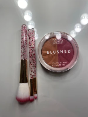 Sminkborstar med glitterhandtag - Tre sminkborstar med transparenta handtag fyllda med rosa glitter och guldiga detaljer. Borsthuvudena är vita med rosa toppar och passar perfekt för applicering av rouge, highlighter eller ögonskugga. Snygg och trendig design som lyfter sminkrutinen. Oanvänd blush i två olika nyanser.