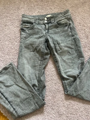 Grå bootcut jeans - Snygga grå jeans med bootcut-modell och dom är lågmidjade. Jeansen har klassiska fem fickor och är tillverkade i ett mjukt denimtyg. 