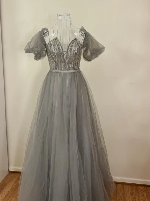 Grå långklänning  - Fin grå klänning som endast använd en gång, i nyskick. Perfekt till bal, fest eller bröllop.  Tveka inte att höra av dig vid frågor eller om du vill lämna ett prisförslag🤍 