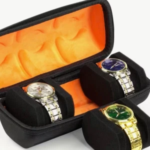 Svart klockförvaringsväska med handtag - Praktisk svart klockförvaringsväska med orange insida och plats för flera klockor. Väskan har hårt skal, dragkedja och ett robust handtag upptill. Perfekt för att organisera och skydda dina klockor när du är på språng.