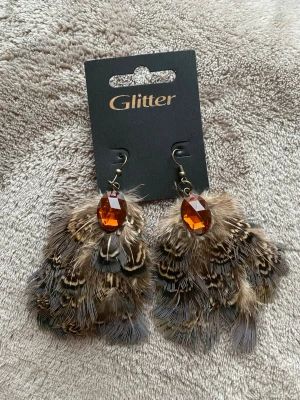 Fjäder örhängen  - Helt nya, säljes pga kommer ej till användning. Djur och rökfritt hem! Fler bilder/mått vid förfrågan 👍