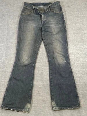 Vintage Wrangler “Broken Twill Denim” low rise flare jeans W30  - Vintage late 90’s-early 2000’s Wrangler “Broken Twill Denim” flare jeans with a proper low rise fit and clean bootcut shape. Natural fading + worn details throughout. Small left knee repair adds character, not flaws. Solid non-stretch denim that holds its shape.  Waist 37.5 cm, inseam 78 cm, length 103.5 cm, rise 24 cm, thigh 28 cm, leg opening 24 cm  Used condition with wear and repair, see pics