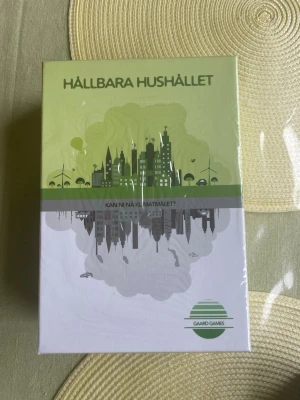 Sällskapsspel Hållbara Hushållet - Sällskapsspelet Hållbara Hushållet från Gaard Games. Spelet har en grön och vit kartong med stadssilhuett och miljötema. Passar 1-6 spelare, rekommenderas från 10 år och tar 60-90 minuter per omgång.