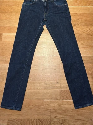 Mörkblå raka jeans från Lee - Snygga mörkblå jeans från Lee (modell Daren) med klassisk rak passform. Jeansen har fem fickor, bälteshällor och stängs med knapp och dragkedja. Tillverkade i slitstark denim som passar perfekt till en avslappnad stil. Strl 32/34