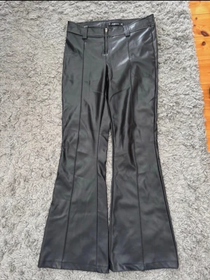 Svarta utsvängda byxor i skinnimitation - Trendiga skinnbyxor från NewYorker