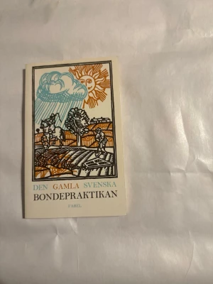 Den gamla svenska Bondepraktikan - En bok med titeln 'Den gamla svenska Bondepraktikan' från Fabel. Omslaget har en färgglad illustration med sol, moln och landskap i brunt, blått och orange. Boken är i pocketformat och har en vit bakgrund med tryckt text i olika färger.