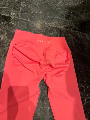 Relode Aura Seamless scrunch tighst - Storlek medium, använda men som nyskick Små i storlek, relodes rekommendation är att gå upp en storlek i dessa tights.                                        Snygga rosa tights från Relode med hög midja och scrunch-detalj bak. Tillverkade i stretchigt material som passar perfekt för träning och gym. Logga i vitt på linningen baktill.