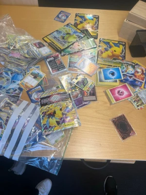Stor samling Pokémonkort och Yu-Gi-Oh! - Säljer en blandad samling Pokémonkort och Yu-Gi-Oh!-kort. Innehåller flera holografiska och specialkort, bland annat Pikachu och andra populära karaktärer. Kort i olika färger och designer, perfekt för samlare eller spelare. Levereras i plastpåsar.