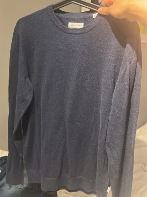 Mörkblå stickad tröja Jack & Jones - Mörkblå stickad tröja från Jack & Jones med rund halsringning och långa ärmar. Tröjan har en enkel och stilren design, perfekt att matcha med jeans eller chinos. Materialet känns mjukt och bekvämt mot huden.