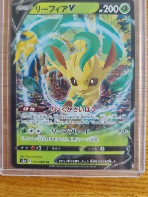 Pokémonkort Leafeon V japansk - Japanskt Pokémonkort med Leafeon V-motiv. Kortet har en färgstark design med gröna, gula och bruna toner och är tillverkat i klassiskt glansigt pappmaterial. Perfekt för samlare eller Pokémon-fans som vill utöka sin kortlek.