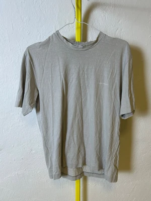 Grå t-shirt från Stone Island  - Denna vara kommer att auktioneras ut på Plick Live den 3 juni klockan 19:00