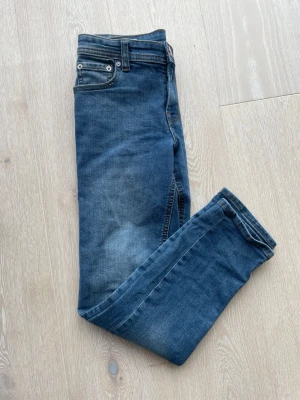 Blå jeans från Jack & Jones - Snygga blå jeans från Jack & Jones i klassisk femficksmodell. Jeansen har en lätt tvättad look och raka ben. Tillverkade i mjukt denimtyg med kontrastsömmar. Perfekta för en avslappnad och trendig stil.