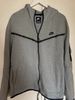 Nike Tech Fleece kofta - Snygg grå hoodie från Nike med hel dragkedja och svarta detaljer.