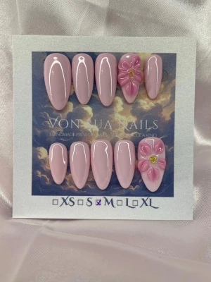 PinkLily (M);Medium Almond - Snygga handgjorda press-on naglar i ljusrosa med glansig finish och en medium lång mandelform. Två av naglarna har handgjorda 3D-blommor i rosa med guld detalj i mitten för extra wow-effekt. Perfekt för dig som vill ha en unik och trendig look. Handgjorda och riktigt detaljerade.M: 16 mm, 12 mm, 12,5 mm, 11,5 mm, 10 mm