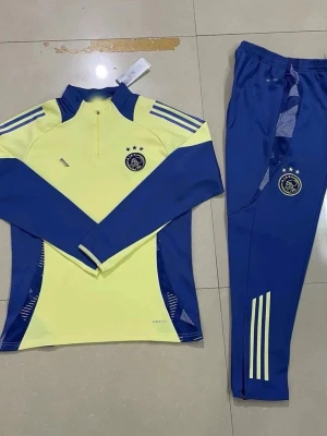 Ajax träningsset gul/blå Adidas - Ajax träningsset från Adidas i gul och blå färg. Tröjan har halv dragkedja, lång ärm och klubbmärke på bröstet. Byxorna är blå med klubbmärke och gula ränder längs benen. Perfekt för fotbollsträning eller sportig stil.