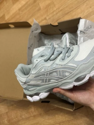Ljusgrå ASICS sneakers - Snygga ljusgrå sneakers från ASICS med mesh och syntetpaneler. Skorna har klassisk ASICS-logga på sidan, vita detaljer och en chunky vit sula. Perfekta för dig som gillar sportig och clean stil.