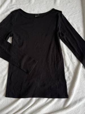 Svart långärmad topp från Gina Tricot (M) - En enkel och stilren svart långärmad topp från Gina Tricot. Toppen har rund halsringning. Perfekt basplagg att matcha med allt i garderoben.