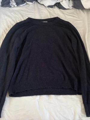 Mörkblå stickad tröja - En enkel och stilren mörkblå stickad tröja med rund halsringning och ribbade muddar vid ärmslut och nederkant. Perfekt basplagg för lager på lager och passar till det mesta. Materialet ser mjukt och bekvämt ut.