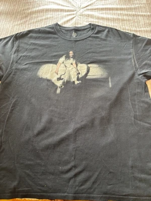 Billie Eilish World Tour 2019 T-shirt - Svart t-shirt från Billie Eilishs World Tour 2019 med tryck av Billie på framsidan och turnédatum på baksidan. Klassisk rund hals och korta ärmar. Perfekt för fans som vill ha en unik merch med coolt motiv.