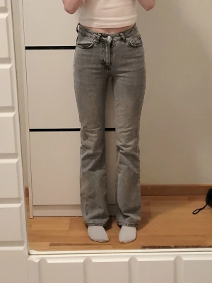 Grå bootcut jeans från Ginatricot  - Jeansen har hög midja och utsvängda ben. 
