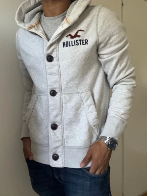 Vintage Hollister Cardigan Med Knappar - Säljer denna otroliga sällsynta och feta Hollister cardigan med knappar | Mycket bra skick, snören fattas| Längd ≈ 65cm, Bredd armhåla - armhåla 55 cm | Modell 175, 68 kg