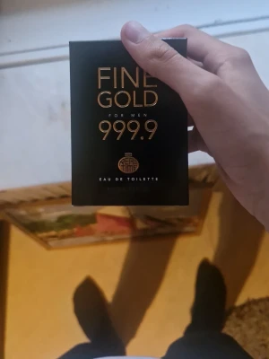 Fine Gold 999.9 Eau de Toilette herr - Maskulin parfym från Real Time, Fine Gold 999.9, Eau de Toilette. Svart rektangulär förpackning med guldiga detaljer och text. Doftolja från Grasse, Frankrike. Passar dig som gillar exklusiv känsla och stilren design.