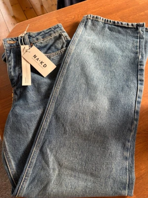 Blå raka jeans från NA-KD - Säljer ett par klassiska blå jeans från NA-KD med rak passform och hög midja. Jeansen har fem fickor och är gjorda i ett slitstarkt denimtyg. Perfekta för en avslappnad och trendig look.