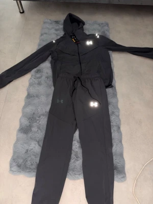 Grå träningsset från Under Armour - Snyggt grått träningsset från Under Armour med matchande jacka och byxor. Byxorna passar på M