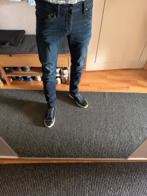 Neuw ”IGGY” skinny fit - Säljer ett par mörkblå slim fit jeans med klassisk femficksdesign och normalhög midja. Jeansen har en snygg tvätt med lätt slitning på låren och smal passform hela vägen ner. Perfekta till sneakers och skjorta för en clean look.