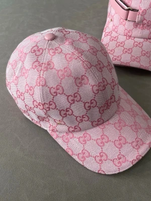 Rosa keps - Säljer en snygg rosa keps med det klassiska mönstret i mörkare rosa över hela kepsen. Kepsen har böjd skärm och en liten metallogo på sidan. Perfekt accessoar för dig som vill sticka ut och addera lite lyx till din outfit.