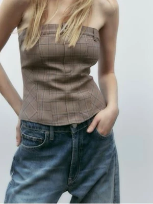 Brun rutig korsettopp - Trendig brun rutig korsettopp med bandeau-modell och markerad midja. Toppen är axelbandslös och har bälteshällor samt knapp- och dragkedjedetalj baktill. 