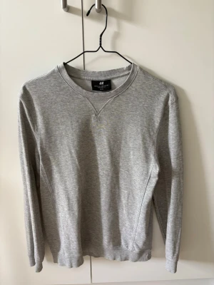 Grå crewneck sweatshirt från H&M - Säljer en stilren grå crewneck sweatshirt från H&M i regular fit. Tillverkad i mjukt material. Perfekt plagg för en avslappnad och snygg look. Passar XS och S