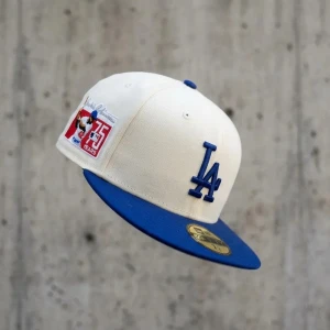 New Era 59FIFTY Jackie Robinson keps - Snygg keps från New Era med broderad hyllning till Jackie Robinson och 75-årsjubileum. Vit bas med blå detaljer och grå undersida på skärmen. Motiv med baseballspelare. Klistermärke inte kvar på framsidan. Annars helt ny. Cirka 60cm runt.