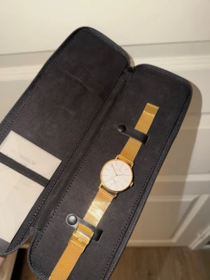 Guldmeshklocka från Carl Edmond - Stilren klocka från Carl Edmond med guldfärgat mesharmband och vit urtavla. Klockan har minimalistisk design med tunna visare och diskret sekundvisare. Perfekt accessoar för dig som gillar klassisk och modern stil.